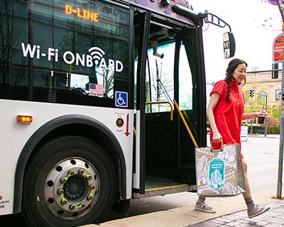 Woman exiting bus with a downtown farmer's market bag